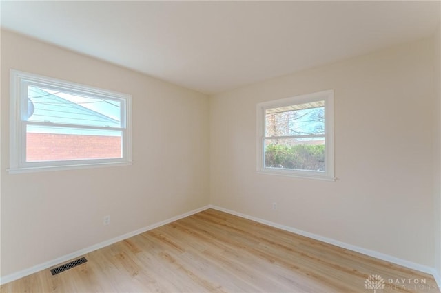 spare room featuring light wood-style flooring, visible vents, and baseboards