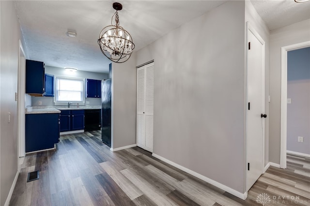 dining area featuring a notable chandelier, visible vents, a textured ceiling, wood finished floors, and baseboards