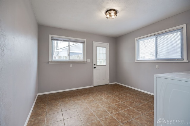 laundry area featuring washer / dryer, plenty of natural light, laundry area, and baseboards