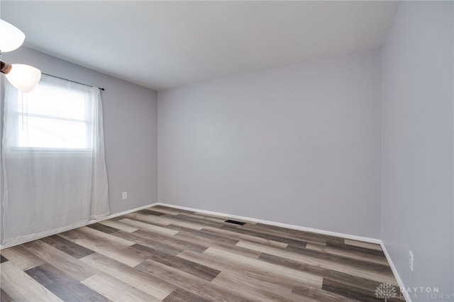 empty room featuring visible vents, baseboards, and wood finished floors