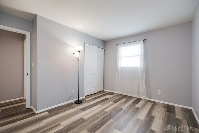 unfurnished bedroom featuring a closet, baseboards, and wood finished floors