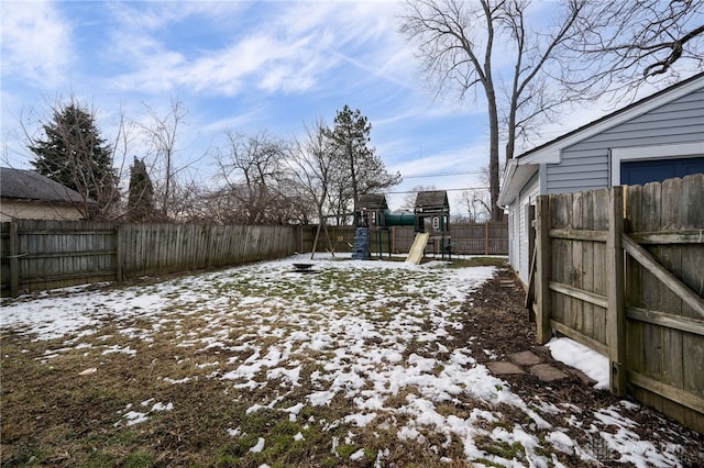 yard covered in snow with a playground and a fenced backyard