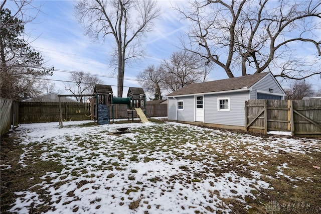 snowy yard featuring a gate, a playground, and a fenced backyard