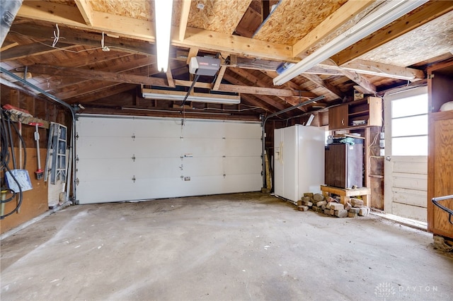 garage featuring white refrigerator with ice dispenser and a garage door opener