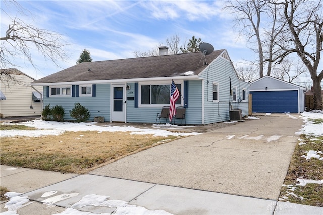 single story home featuring a shingled roof, a detached garage, a chimney, an outbuilding, and central AC