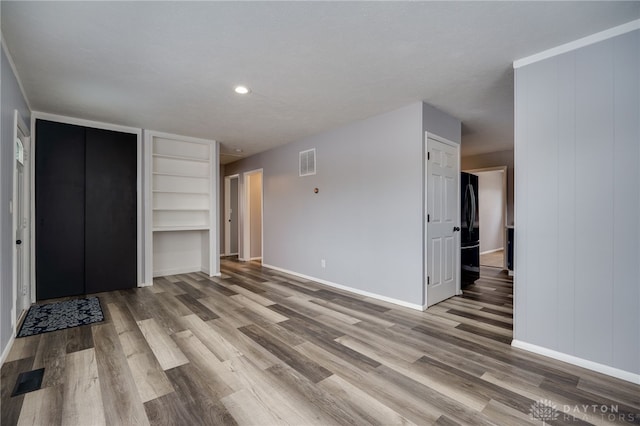 unfurnished bedroom with light wood finished floors, baseboards, visible vents, and freestanding refrigerator