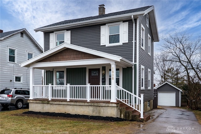 view of front of house featuring aphalt driveway, a chimney, covered porch, a garage, and an outdoor structure