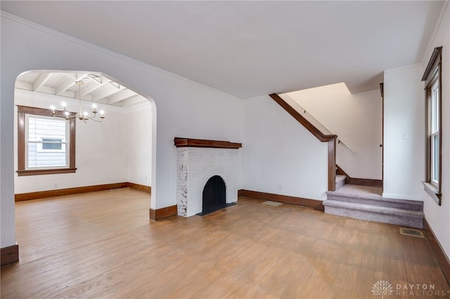 unfurnished living room with arched walkways, an inviting chandelier, visible vents, and light wood-style floors