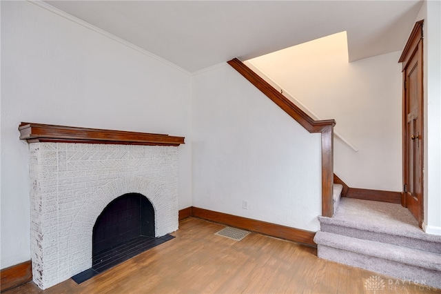 unfurnished living room featuring light wood-style flooring, stairs, baseboards, and a fireplace