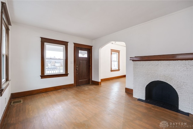 entryway with a fireplace, wood finished floors, visible vents, and baseboards