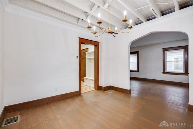 empty room with arched walkways, a notable chandelier, wood finished floors, visible vents, and beamed ceiling