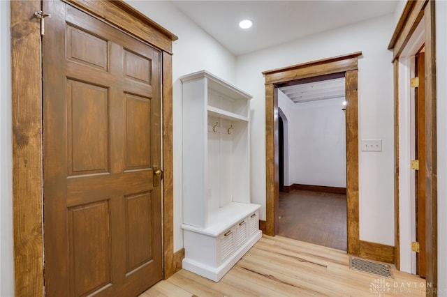 mudroom featuring arched walkways, light wood finished floors, visible vents, and baseboards