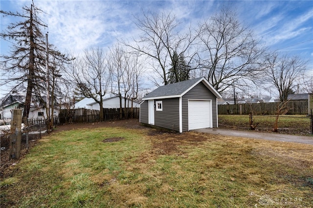 view of yard featuring a fenced backyard, an outdoor structure, driveway, and a detached garage