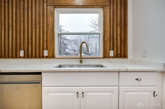 kitchen featuring light stone countertops, white cabinetry, a wealth of natural light, and a sink