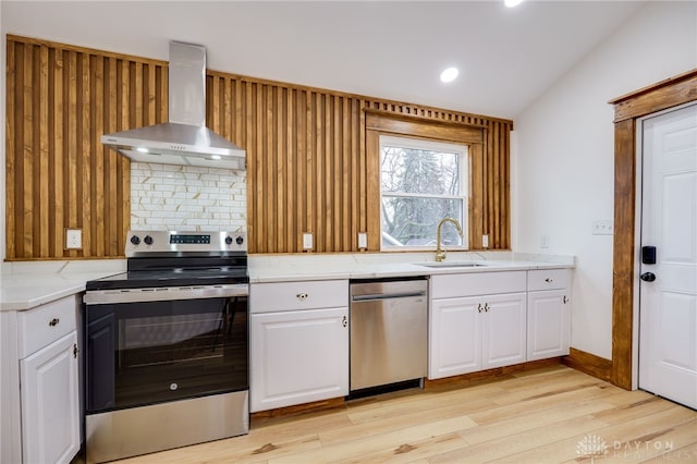 kitchen with light countertops, wall chimney range hood, a sink, and appliances with stainless steel finishes