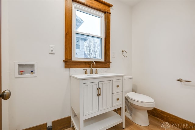 bathroom featuring baseboards, vanity, toilet, and wood finished floors