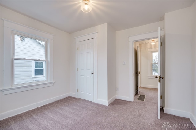 unfurnished bedroom with light carpet, multiple windows, and visible vents