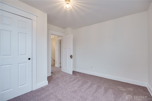 unfurnished bedroom featuring light carpet and baseboards