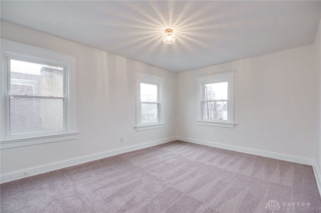 empty room featuring baseboards and light colored carpet