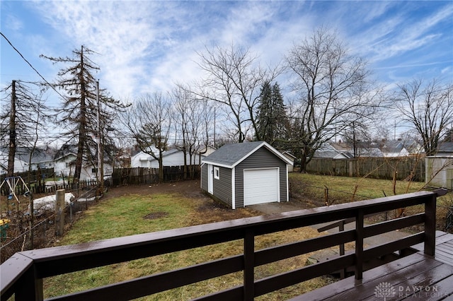 view of yard with driveway, a fenced backyard, a detached garage, and an outdoor structure