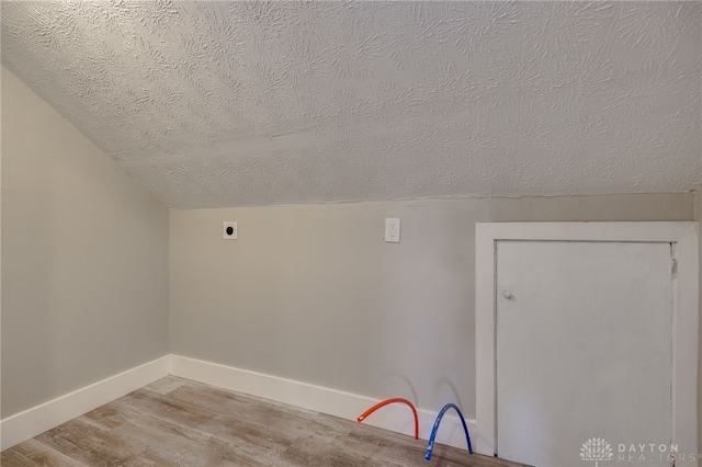 washroom with a textured ceiling, light wood-style flooring, hookup for an electric dryer, laundry area, and baseboards