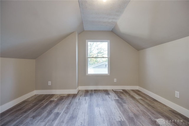 additional living space featuring a textured ceiling, baseboards, and wood finished floors