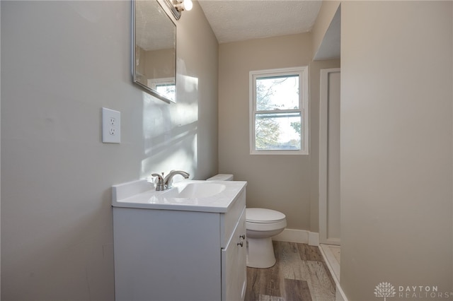 bathroom with baseboards, toilet, wood finished floors, a textured ceiling, and vanity