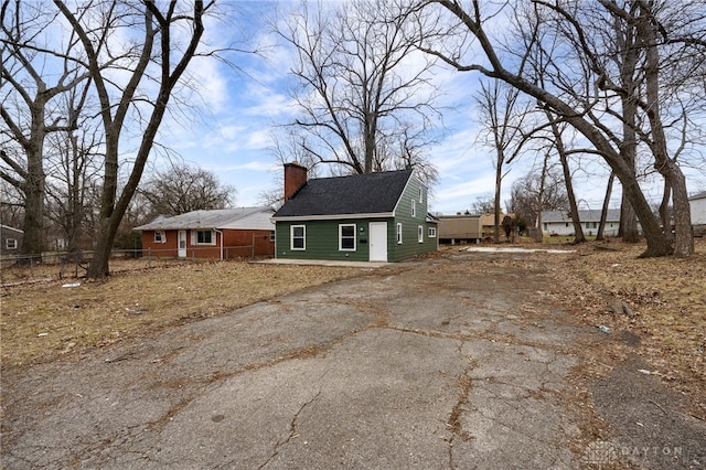 view of side of property with driveway, fence, and a chimney