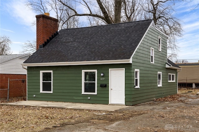 exterior space featuring a shingled roof, fence, and a chimney