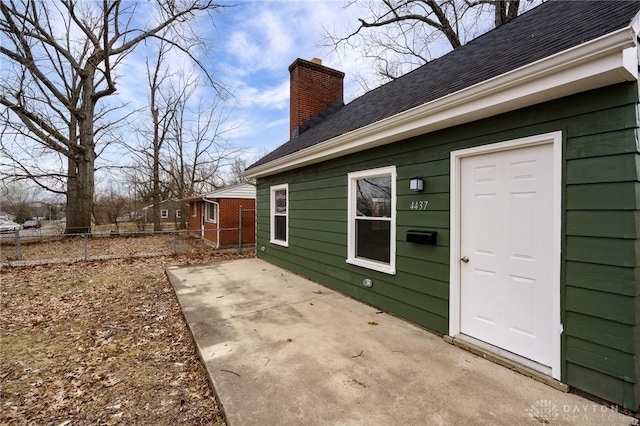 view of home's exterior with a chimney, a patio area, and fence