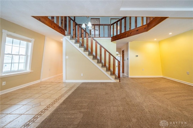 unfurnished living room featuring a notable chandelier, recessed lighting, stairway, carpet flooring, and baseboards