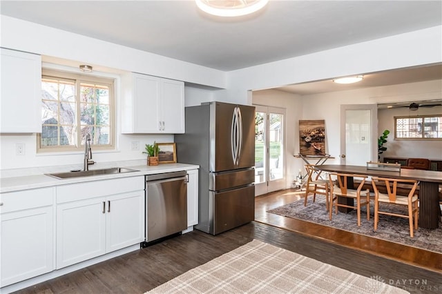 kitchen with dark wood-style floors, appliances with stainless steel finishes, light countertops, white cabinetry, and a sink