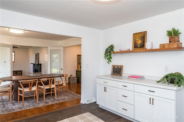 dining space featuring dark wood-type flooring, a fireplace, and visible vents