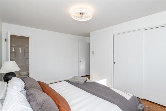 bedroom with ensuite bath, a closet, and wood finished floors