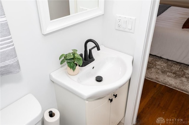 half bathroom featuring toilet, wood finished floors, and vanity