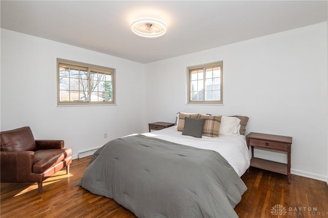 bedroom featuring a baseboard heating unit, multiple windows, and dark wood-style floors