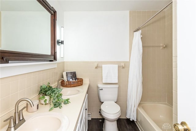 bathroom with double vanity, tile walls, a sink, and wainscoting