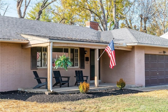 view of front of home with a porch, a garage, brick siding, roof with shingles, and a chimney