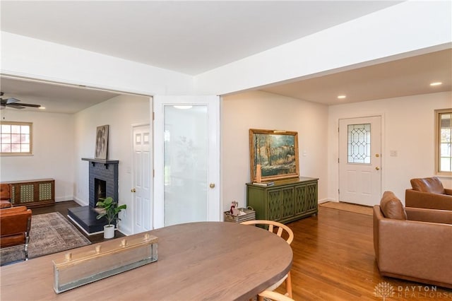 dining room with ceiling fan, plenty of natural light, a fireplace, and wood finished floors