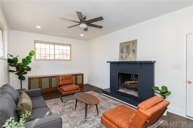 living area featuring recessed lighting, a brick fireplace, baseboards, and wood finished floors