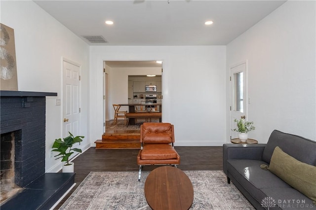 living area featuring baseboards, a fireplace, visible vents, and dark wood-style flooring