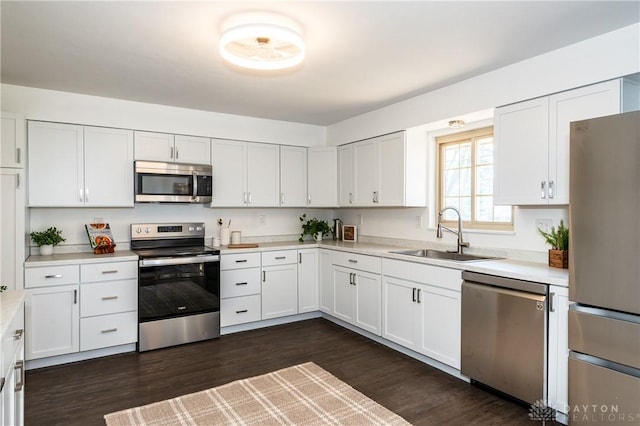 kitchen with dark wood-style flooring, light countertops, appliances with stainless steel finishes, white cabinetry, and a sink