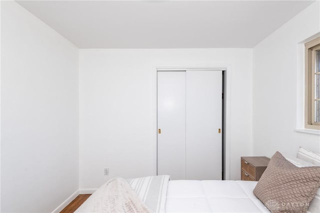 bedroom with a closet, baseboards, and wood finished floors