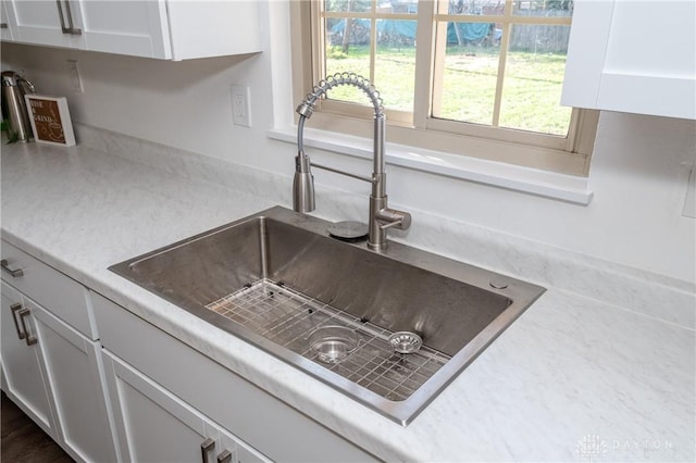 interior details with white cabinets, light countertops, and a sink