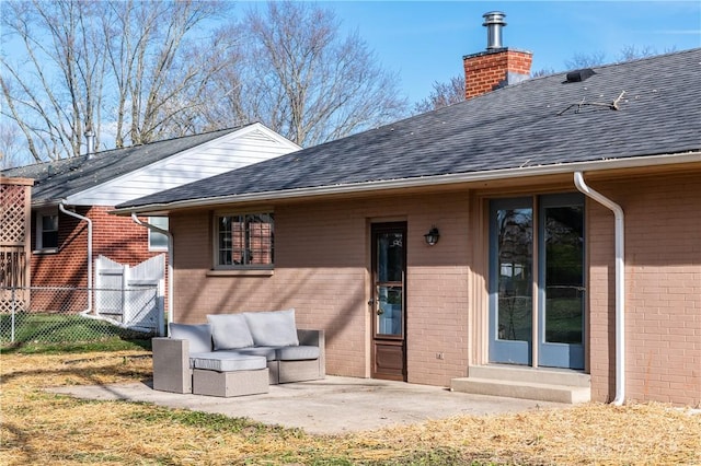 back of property with entry steps, a patio, a chimney, roof with shingles, and brick siding