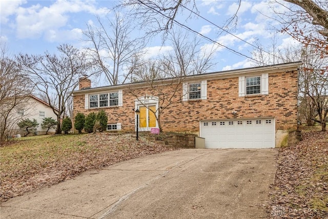 bi-level home featuring an attached garage, a chimney, concrete driveway, and brick siding