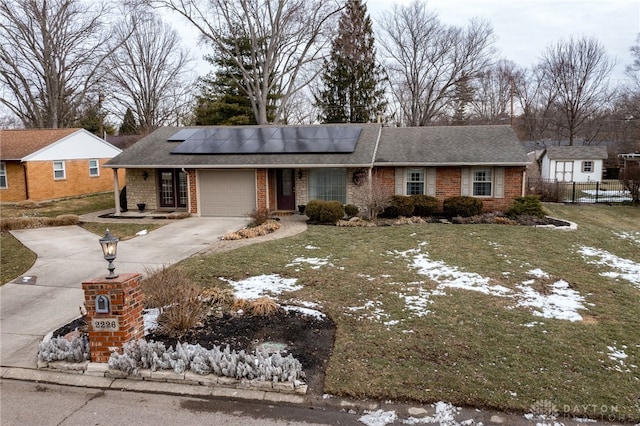 single story home featuring brick siding, solar panels, a front yard, a garage, and driveway