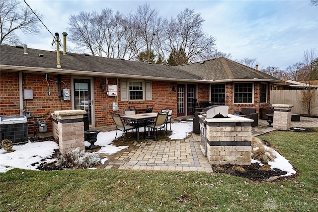 rear view of property featuring an outdoor kitchen, a patio, fence, central AC, and brick siding