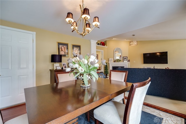 dining room with lofted ceiling, a fireplace, wood finished floors, and ornate columns