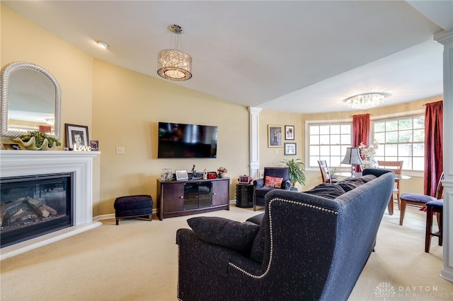 living area featuring lofted ceiling, light carpet, baseboards, a glass covered fireplace, and ornate columns